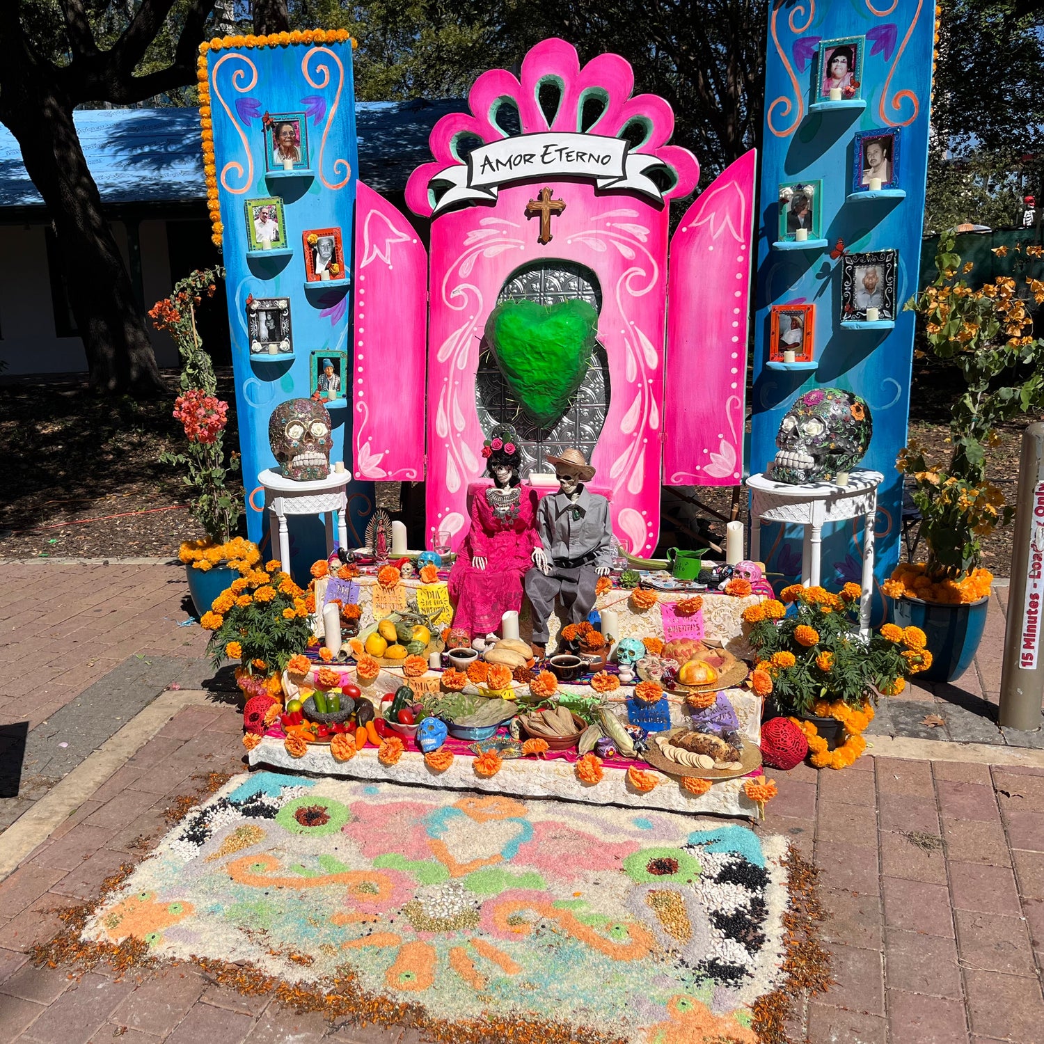 Decorative altar with colorful elements and 'Muertos Fest' sign in an outdoor setting